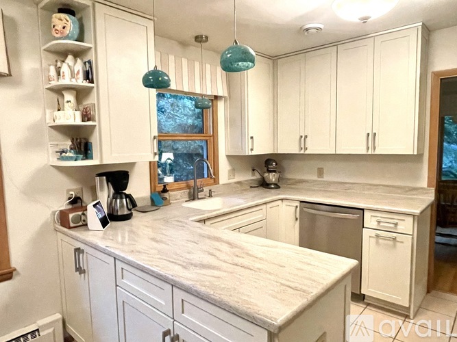 A kitchen with white cabinets and a marble countertop.