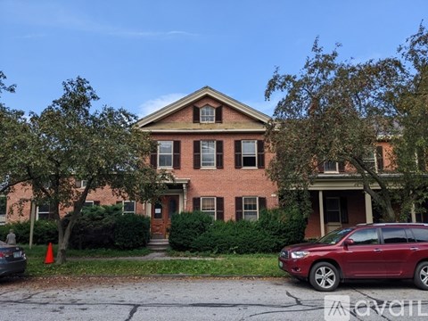 A red brick house with a car parked in front.