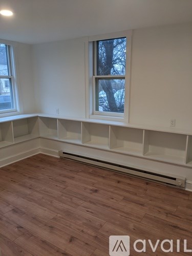 A room with wooden floors and a window with a view of trees outside.