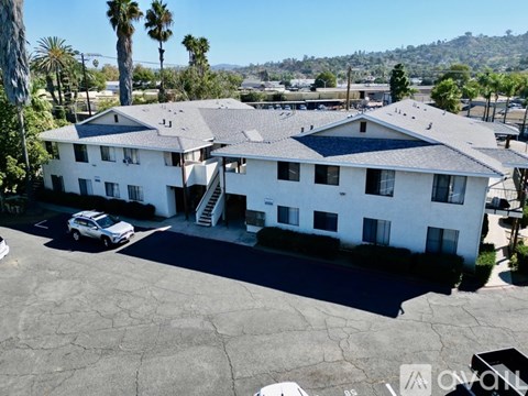 A white building with a black roof and a car parked in front.