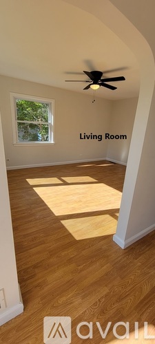 A living room with a ceiling fan and wooden flooring.