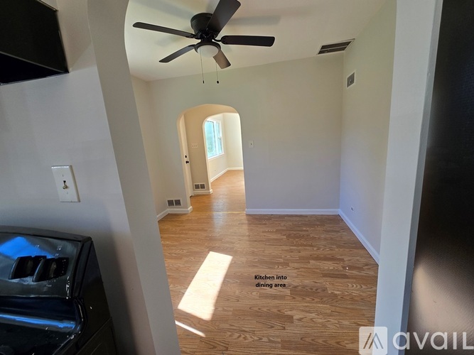 A kitchen area with a fan and wooden flooring.