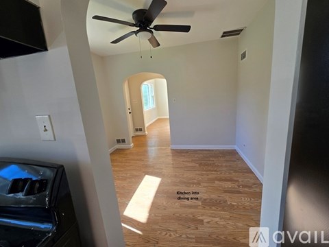 A kitchen area with a fan and wooden flooring.