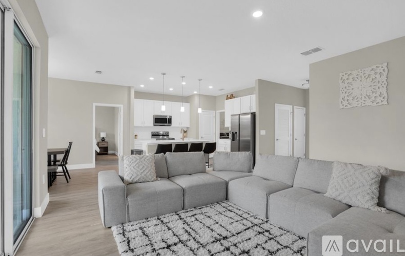 A modern living room with a grey sofa and a black and white rug.