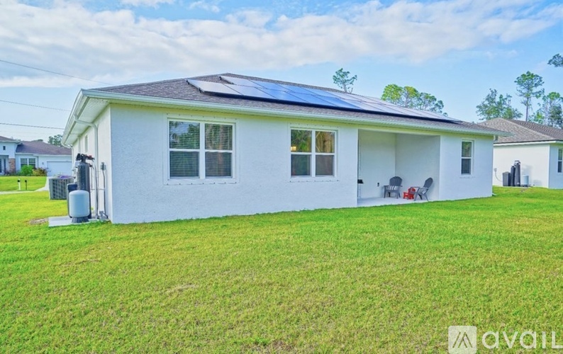 A white house with a solar panel on the roof.