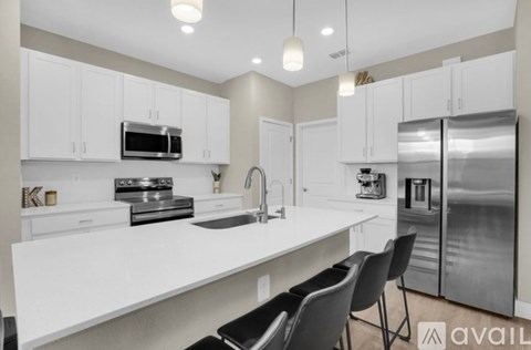 A modern kitchen with white cabinets and stainless steel appliances.