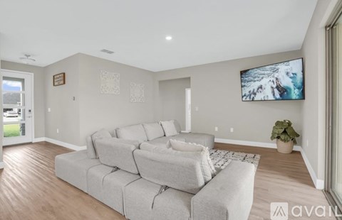 A living room with a grey sofa and a television mounted on the wall.