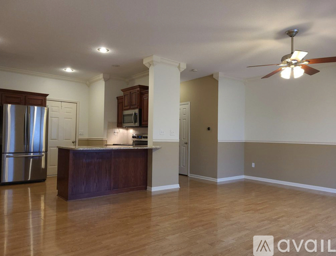 A kitchen with a refrigerator, microwave, and a countertop with a fan above it.