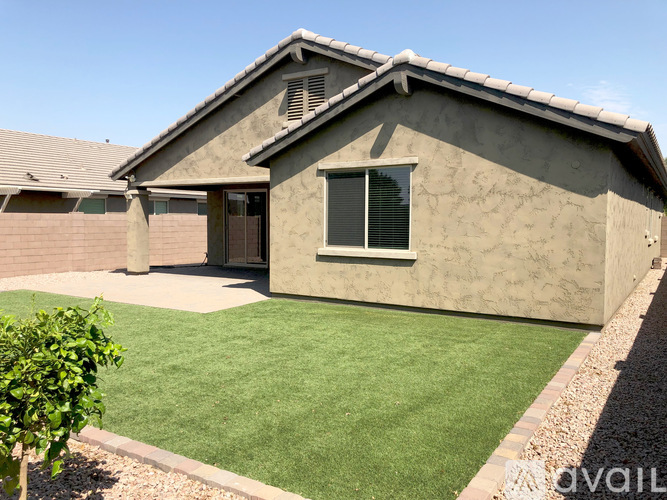 A house with a brown roof and a green lawn in front.