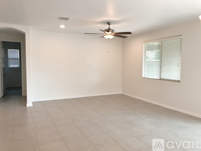 A spacious room with a ceiling fan and a window with blinds.
