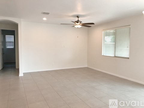 A spacious room with a ceiling fan and a window with blinds.