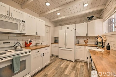A kitchen with white cabinets and a wooden floor.