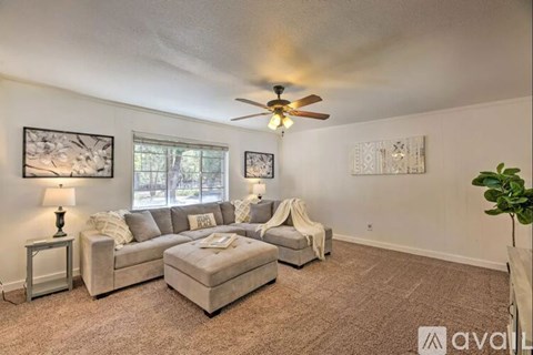 A living room with a grey couch, a white armchair, and a small table with a lamp on it.