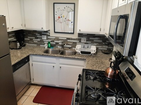 A kitchen with a stove, sink, and cabinets.