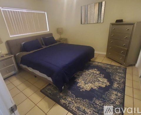 A bedroom with a bed, dresser, and a rug.