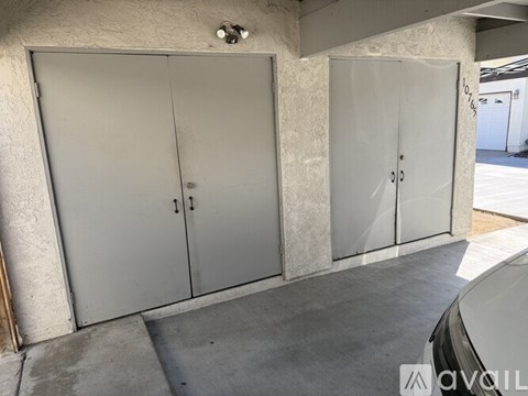 Two white doors in a concrete room.