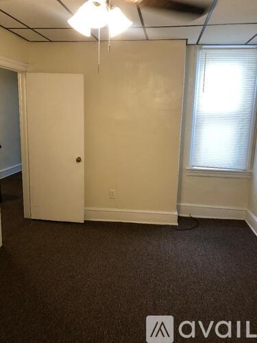 A room with a carpeted floor, a door, and a window.
