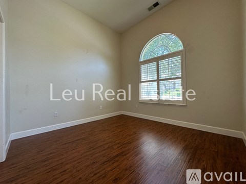 A room with a wooden floor and a window with a view of trees.
