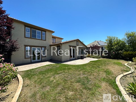 A house with a well-maintained lawn and a clear blue sky above.