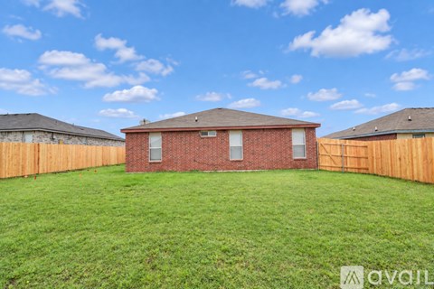 A red brick house with a brown fence and a green lawn.
