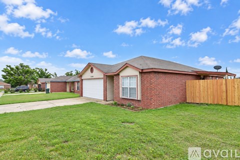 A house with a brown brick exterior and a white garage door is for sale.