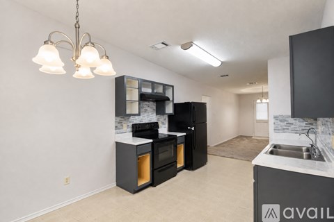 A kitchen with black cabinets and a white countertop is available for rent.