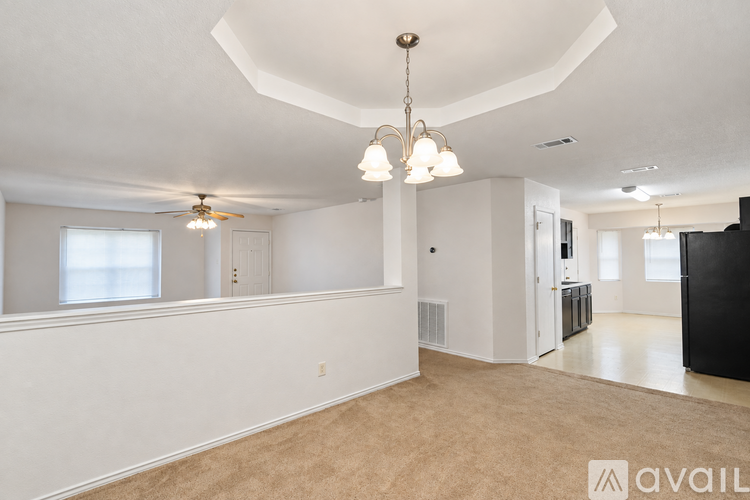 A spacious living room with a fan and a chandelier.