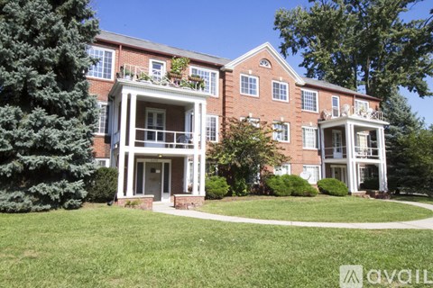 A red brick building with a balcony and a tree in front.