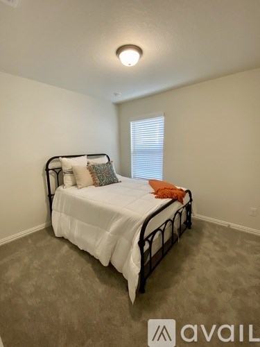 A bedroom with a bed, pillows, and a window with blinds.
