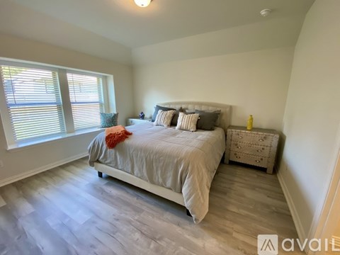 A bedroom with a bed, nightstand, and window.