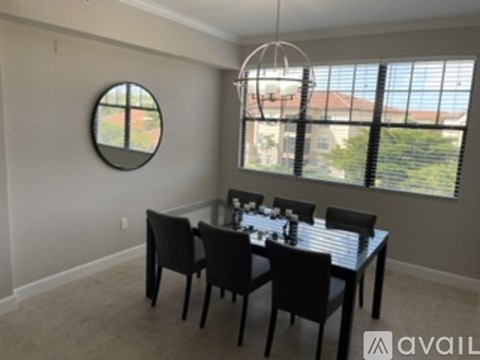 A dining room with a round mirror and a table with chairs.