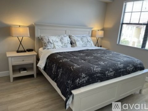 A bedroom with a large bed and two lamps on either side of the bed.