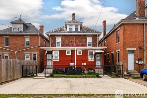 A red brick house with a black fence in front.
