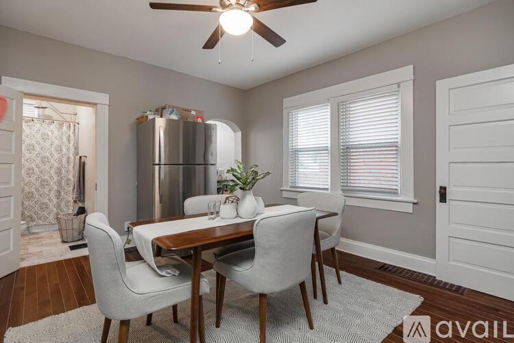 A dining room with a table set for two and a refrigerator in the background.