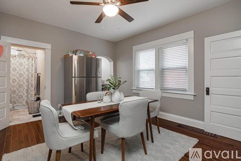 A dining room with a table set for two and a refrigerator in the background.