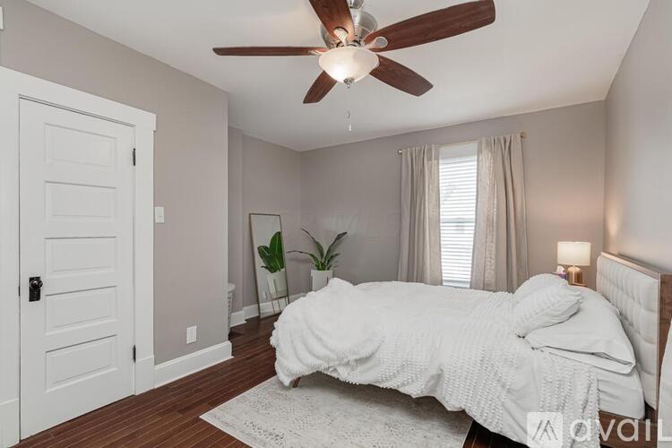 A bedroom with a bed, a ceiling fan, and a door.