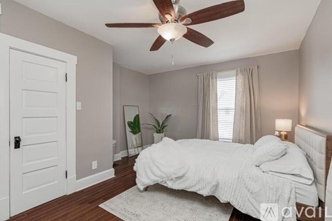 A bedroom with a bed, a ceiling fan, and a door.
