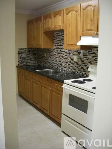 A kitchen with wooden cabinets and a white stove top oven.