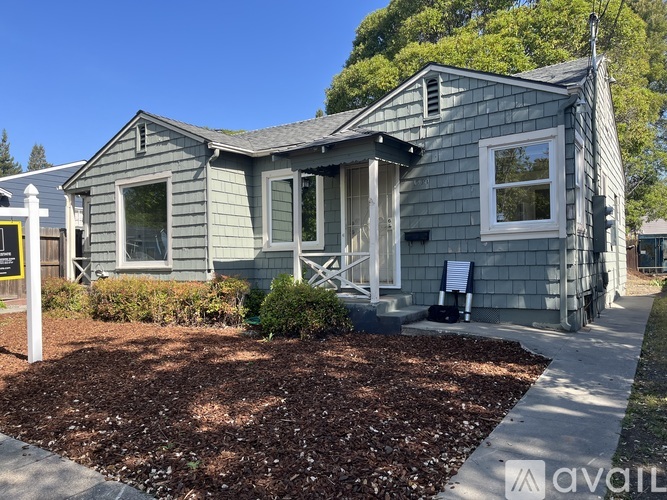 A small house with a grey exterior and a white picket fence.