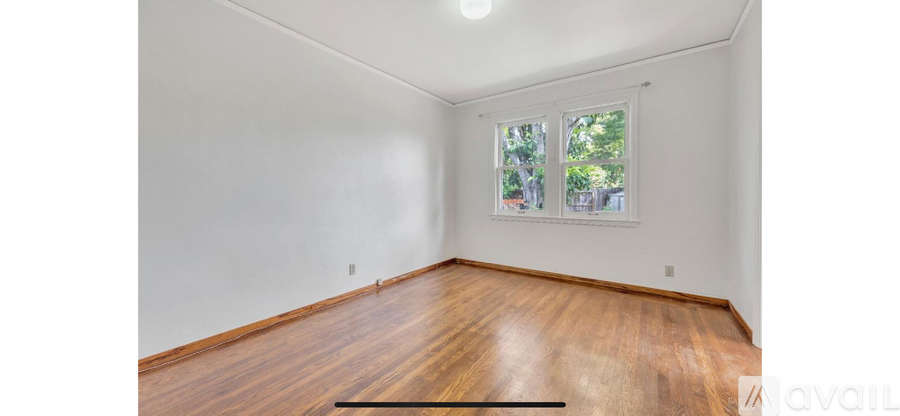 A room with a window and wooden floors is available for rent.
