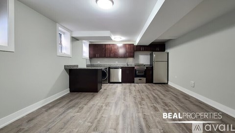 A kitchen area with a refrigerator, sink, and cabinets.