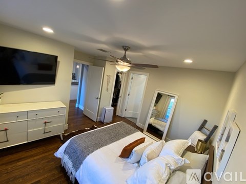A bedroom with a large bed and a television mounted on the wall.