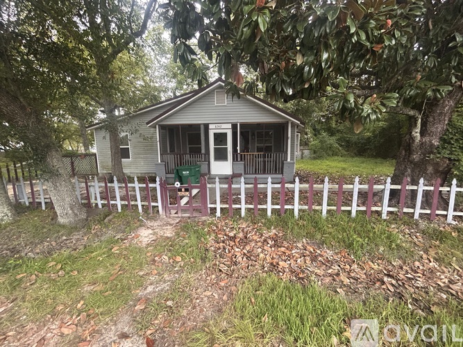 A small house with a white picket fence in front of it.