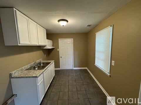 A kitchen with white cabinets and a marble countertop.