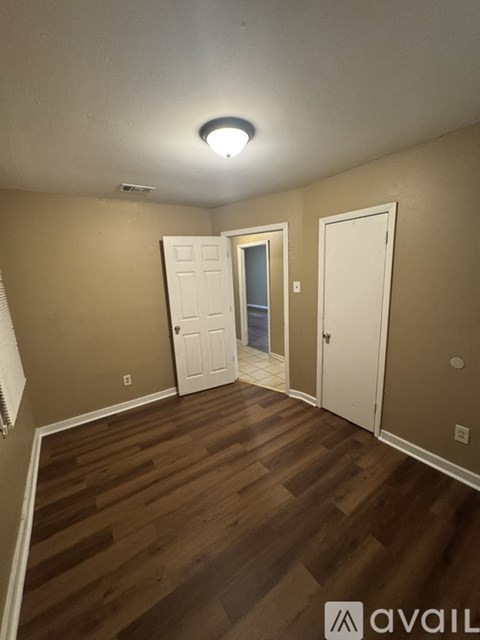 A room with wooden floors and two white doors.