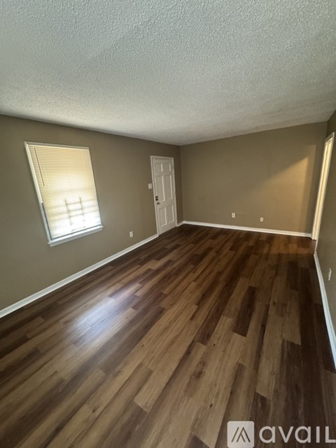 A room with wooden flooring and a window with blinds.