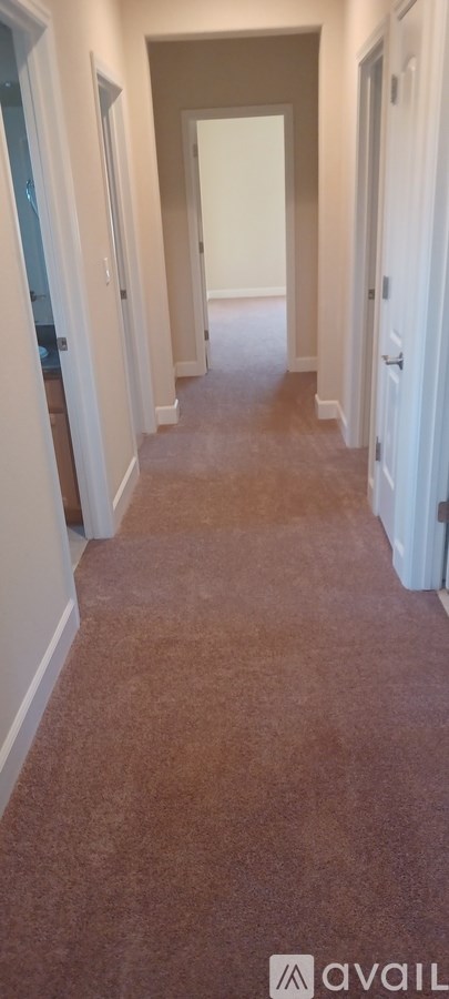 A long hallway with carpeted floors and white walls.