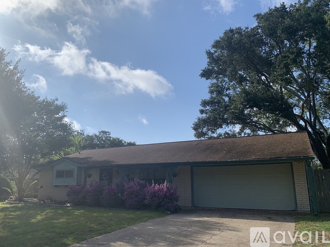 A house with a garage and a tree in front.