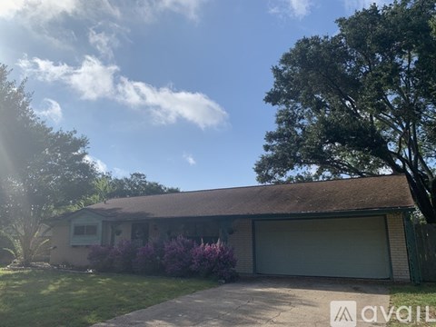 A house with a garage and a tree in front.