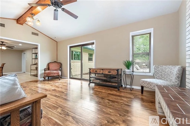 A living room with a ceiling fan and sliding glass doors.